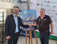 Oberbürgermeister Claus Ruhe Madsen (li.) und BHV Nord-Vorsitzender Rainer Voß vor dem Plakat der 84. Warnemünder Woche